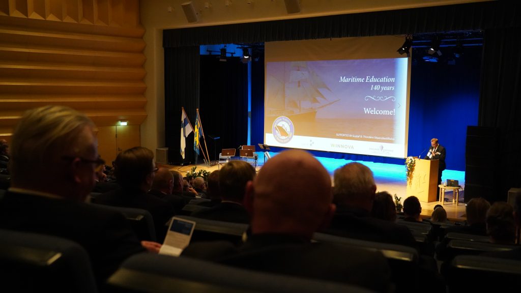 Antti Kaikkonen puhuu puhujankorokkeella auditoriossa.