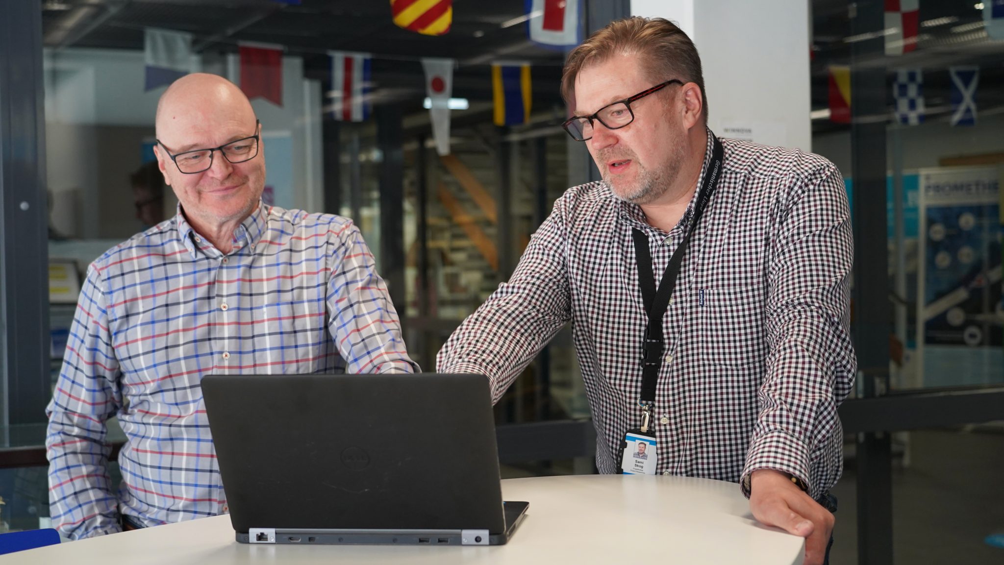 Heikki Koivisto and Sami Skog discussing by a table, a laptop in front of them.