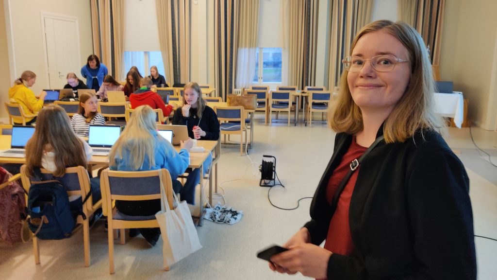 Projektipäällikkö Nina Savela etualalla, taka-alalla ChangeMakers-hankkeeseen osallistuneita lukiolaisia tehtäviensä parissa.