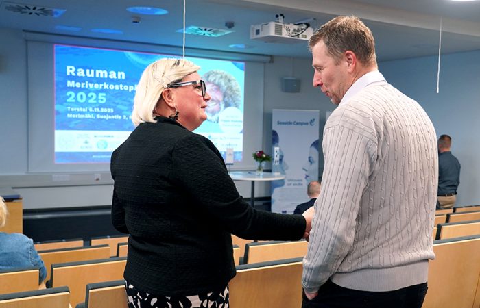 Kaksi ihmistä kättelevät auditoriossa.