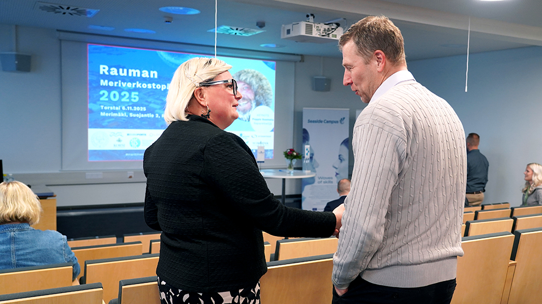 Kaksi ihmistä kättelevät auditoriossa.