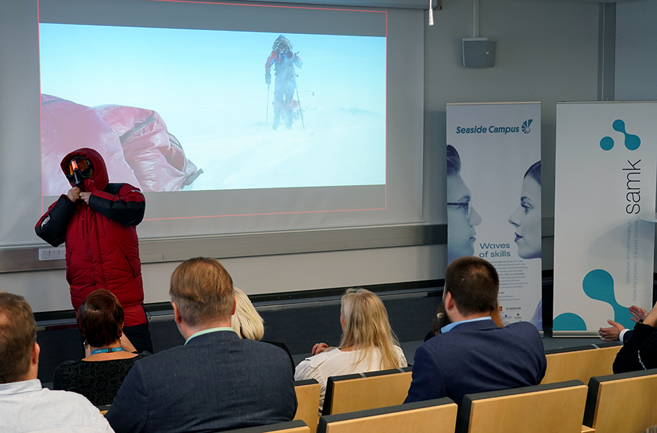 Poppis Suomela suurta talvitakkia päältään auditorion edessä.