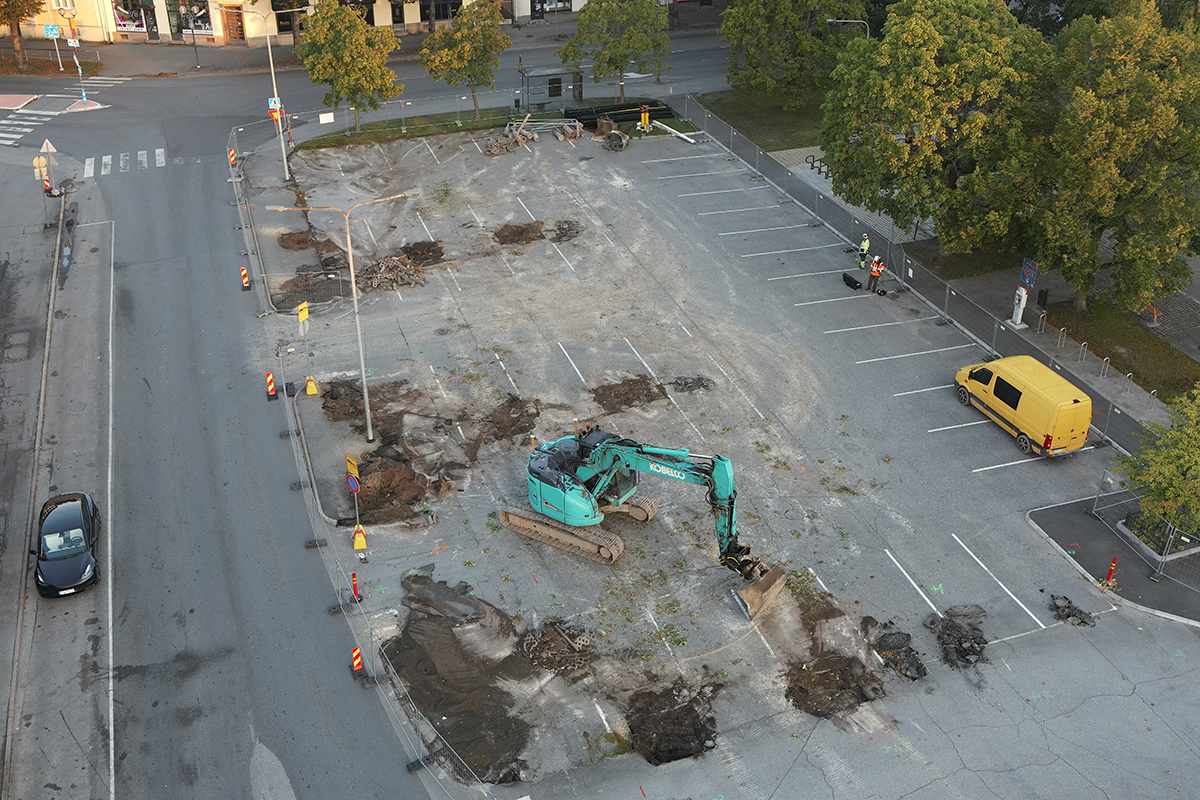 Aerial view of the parking lot. The parking lot is empty. There is an excavator in the middle of the parking lot.