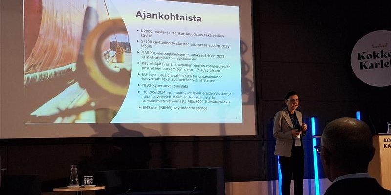 Henkilö esittämässä tapahtuman aikataulua. Taustalla diaesitys.