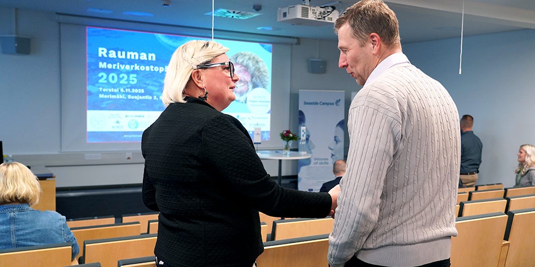 Kaksi ihmistä kättelevät auditoriossa.