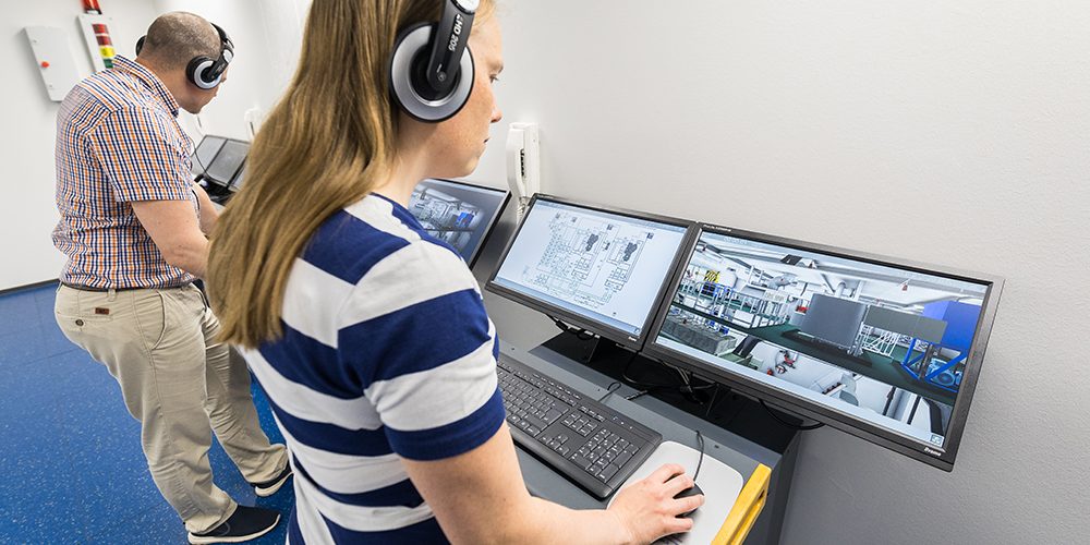 Two people are standing in front of computers doing 3D modelling.