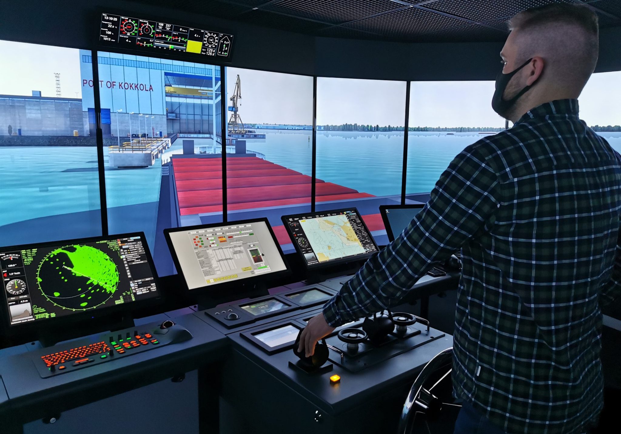 Henkilö ajaa laivasimulaattoria. Henkilöllä koronamaski.