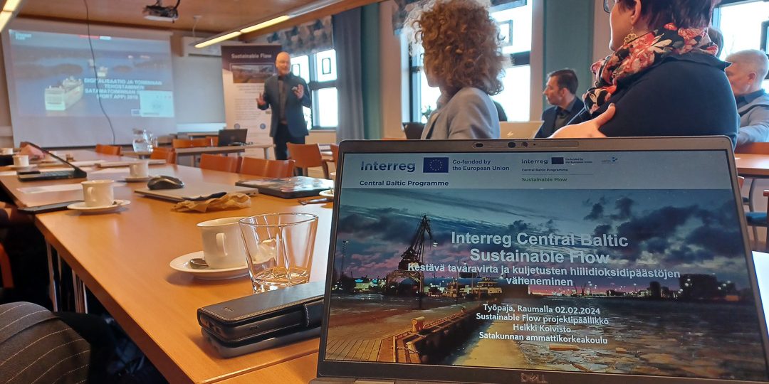 Sustainable Flow Sidosryhmätapaaminen 03 Kuvassa tietokoneen ruutu ja taustalla sumeana henkilöitä.