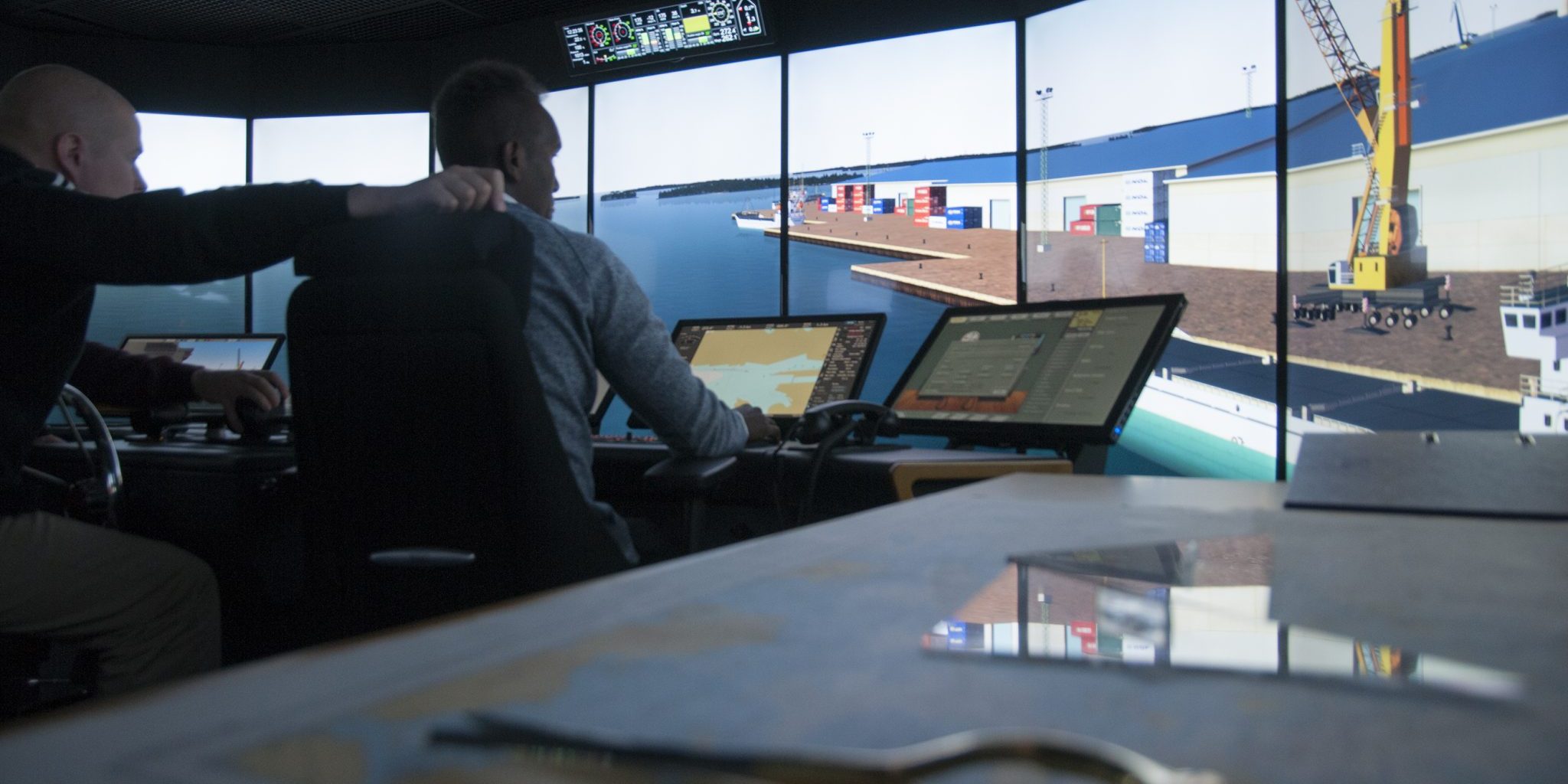 Two men steer the ship in a simulator.