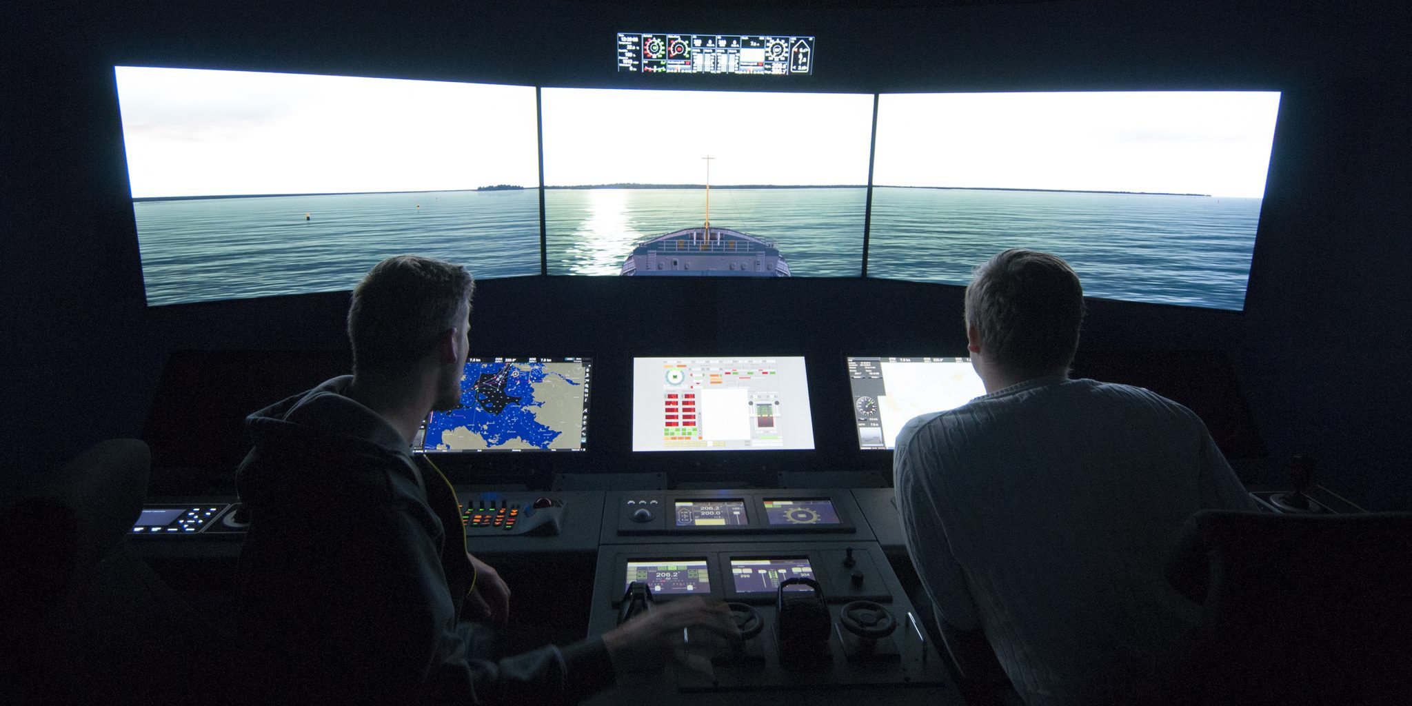 Two people working at a maritime simulator.